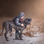 large black dog with his young boy playing outside during photography session by Vicky from Champagne Photography
