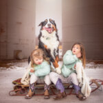 young girls outside at the farm with their dog on a sled in Brock Township Ontario
